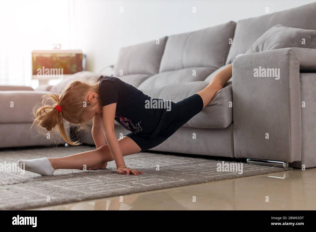 Nette Turnerin Praxis Stretching jeden Morgen. Mädchen Kind Stretching auf Teppich. Zeit für morgendliche Stretching Stockfoto