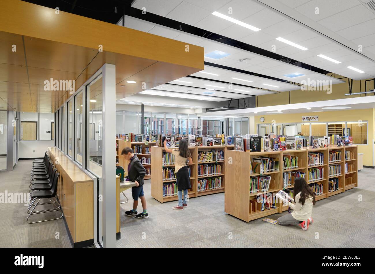 Grundschule Bibliothek mit Studenten lernen und Bücher suchen. Stockfoto