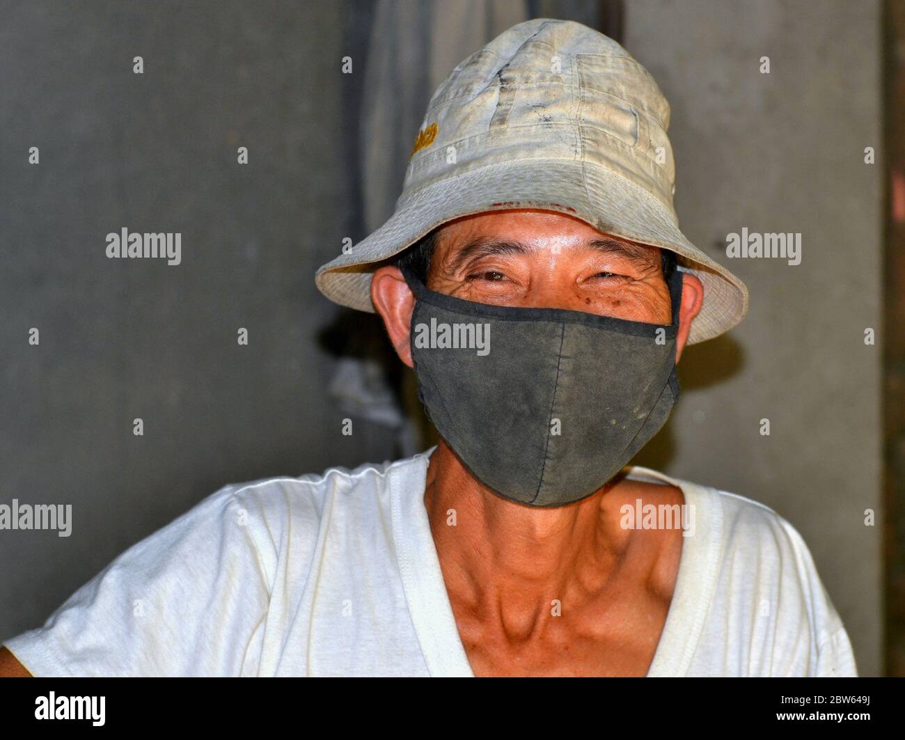 Vietnamesische Reismühlenarbeiter trägt eine waschbare improvisierte Anti-Verschmutzung Tuch Gesichtsmaske. Stockfoto
