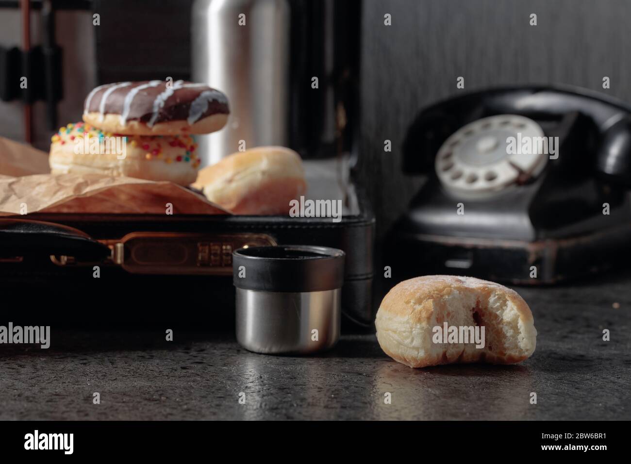 Altes schwarzes Telefon und unfertiges Mittagessen. Donuts und Thermoskanne im Koffer. Stockfoto