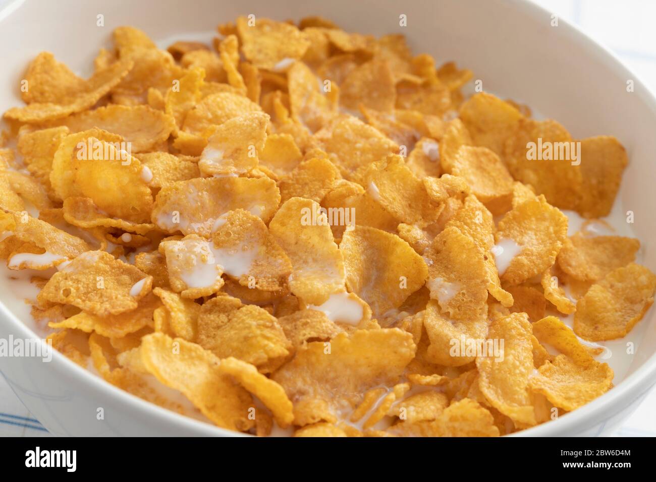 Schüssel mit traditionellen Cornflakes und Milch Nahaufnahme isoliert auf weißem Hintergrund Stockfoto