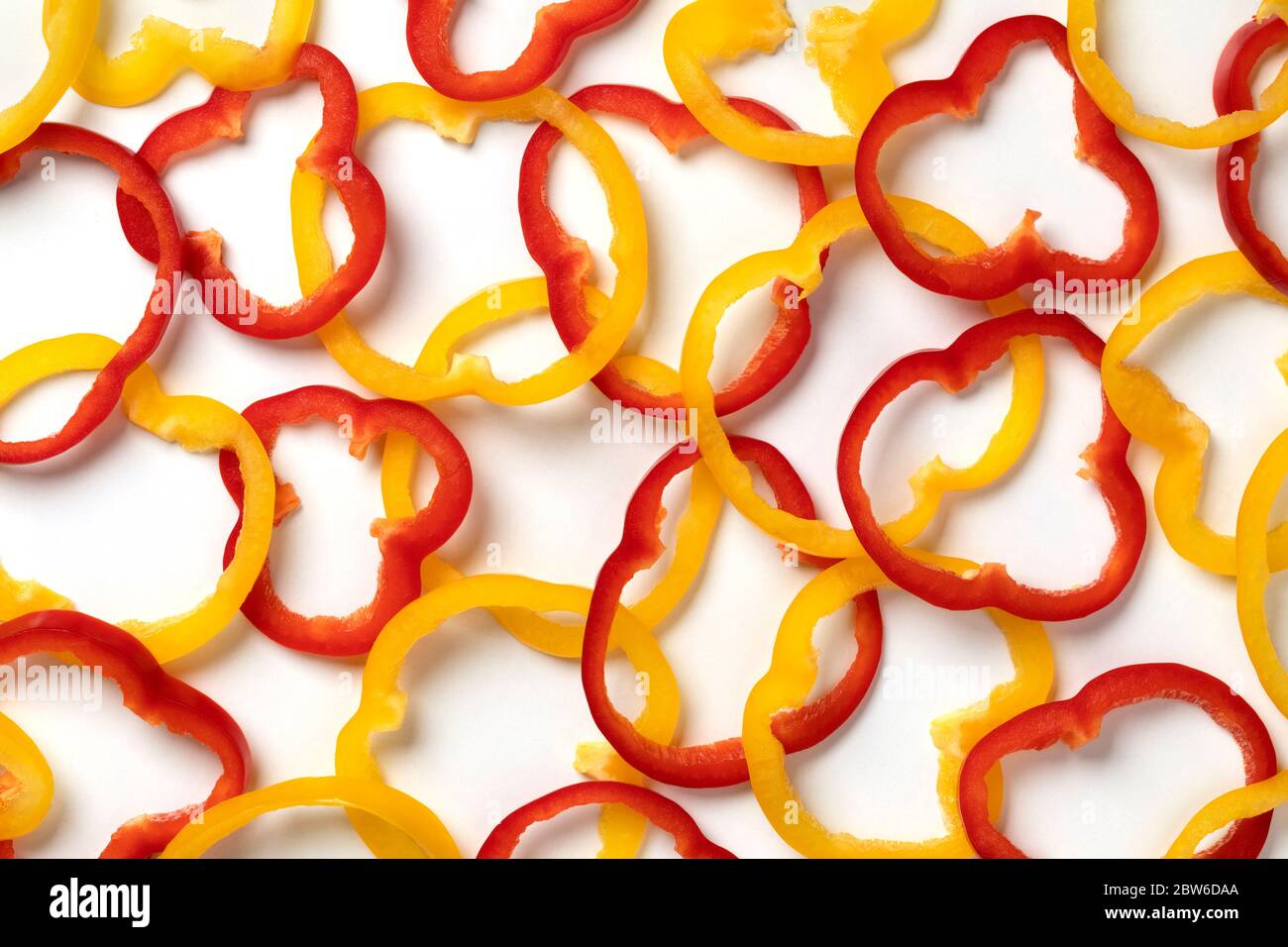 Frisch geschnittene Ringe aus roter und gelber Paprika schließen sich auf weißem Hintergrund Stockfoto