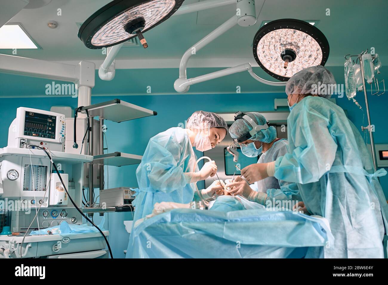 Moderne Chirurgie in einem technologisch fortgeschrittenen Krankenhaus. Heller Raum der Intensivpflege. Ärzte und Assistenten, die im Operationssaal arbeiten, retten Leben. Stockfoto