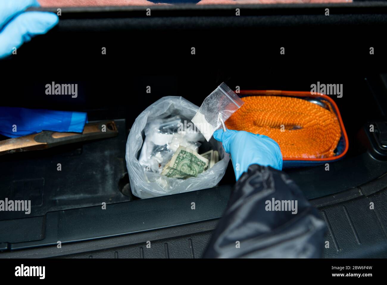 Die Polizei findet einen Beutel mit Geld und Drogen in der Kofferraum eines Häftlings Stockfoto