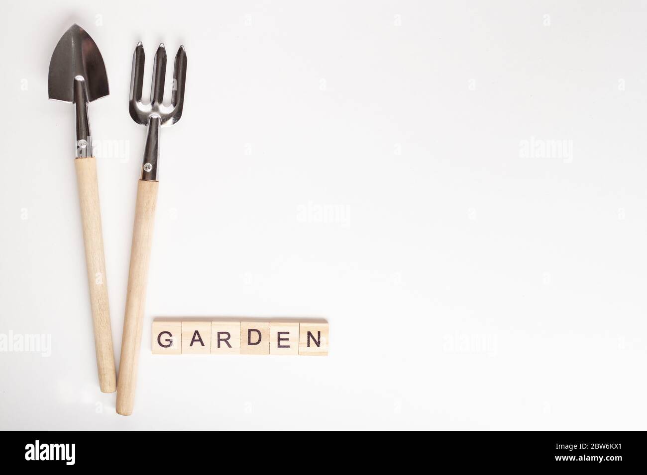 Werkzeuge für die Gartenarbeit zu Hause. Copyspace für Text, Draufsicht. Flatlay auf weißem Hintergrund. GARTENTEXT aus Holzwürfel. Schriftzug GARTEN, Schriftzug i Stockfoto