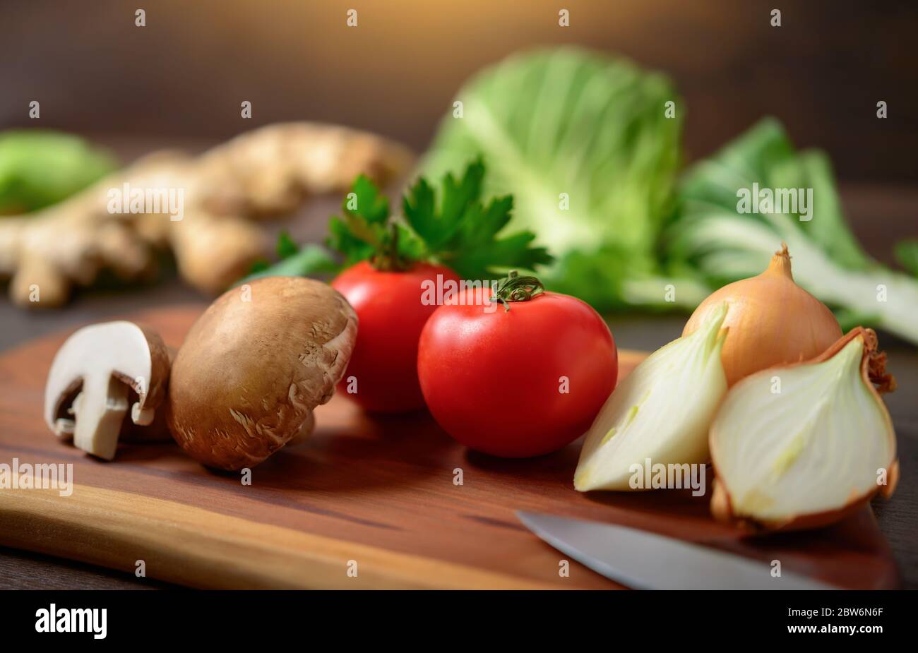 Gemüse auf einem Holzbrett zum Kochen zubereiten. Ein Nahaufnahme mit flachen Fokus zeigt bunte, nahrhafte und köstliche Zutaten als Stockfoto