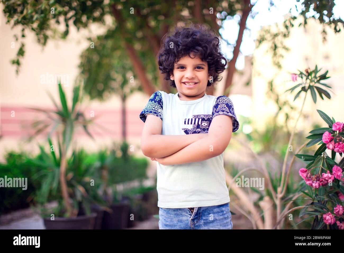 Ein Porträt von lächelnden Jungen mit lockigen Haaren im Freien. Kinder und Emotionen Konzept Stockfoto