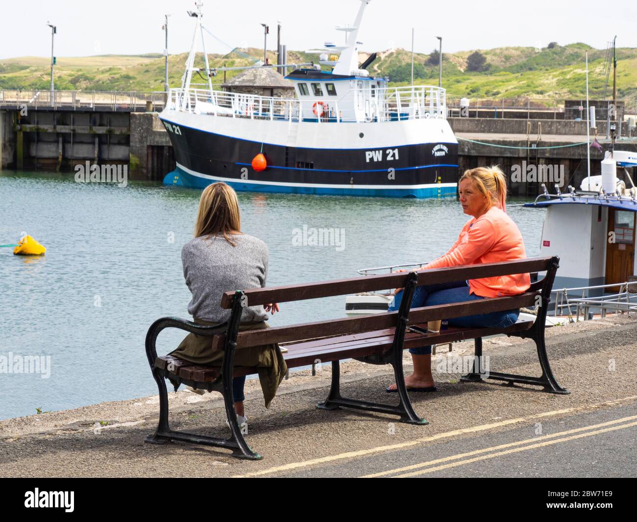 Zwei Freunde treffen sich für ein Paar unter sozialen Distanzierungsregeln, Padstow, Cornwall, Großbritannien Mai 2020 Stockfoto