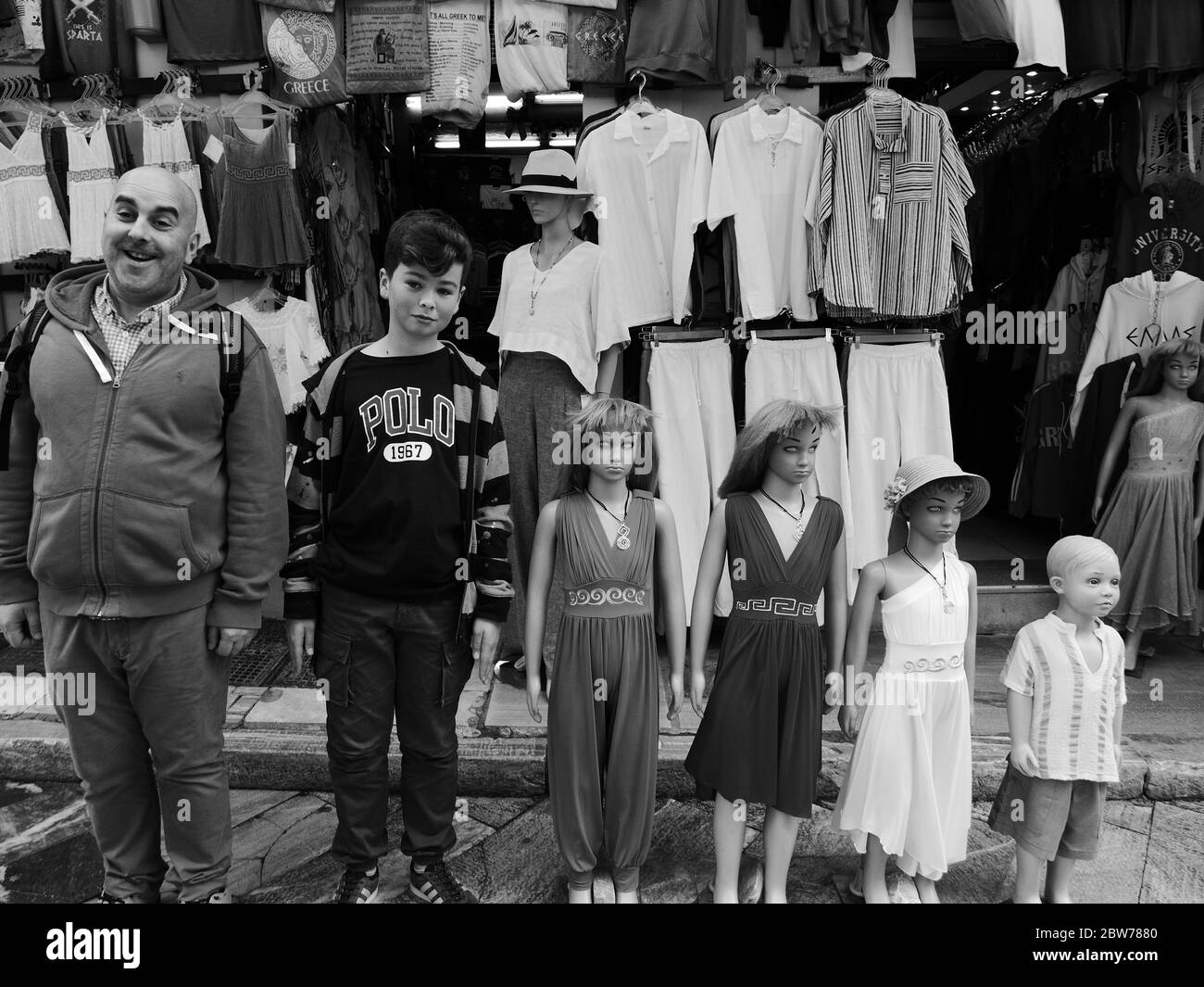 Amüsantes Schwarz-Weiß-Foto von Leuten, die sich als Dummies/Shop-Mannequin-Modelle vor einem Kleiderladen in Athen ausstellen - aufgereiht in einer Reihenmischung Stockfoto