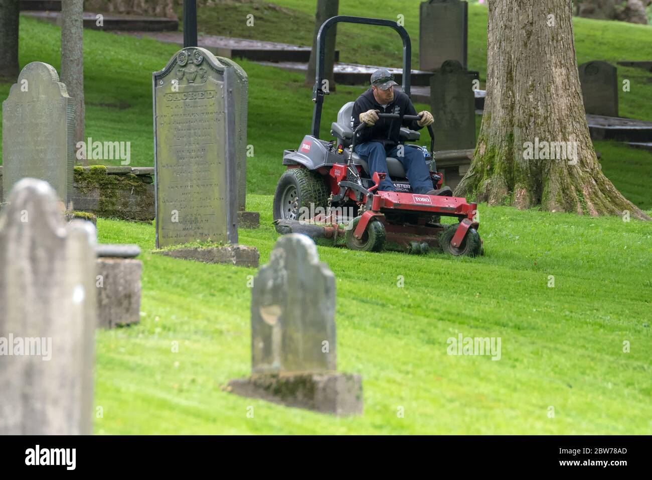 Saint John, New Brunswick, Kanada - 25. Juli 2018: Ein Mann, der einen Rasenmäher benutzt, um den Rasen in einem Grabhof zu mähen. Stockfoto