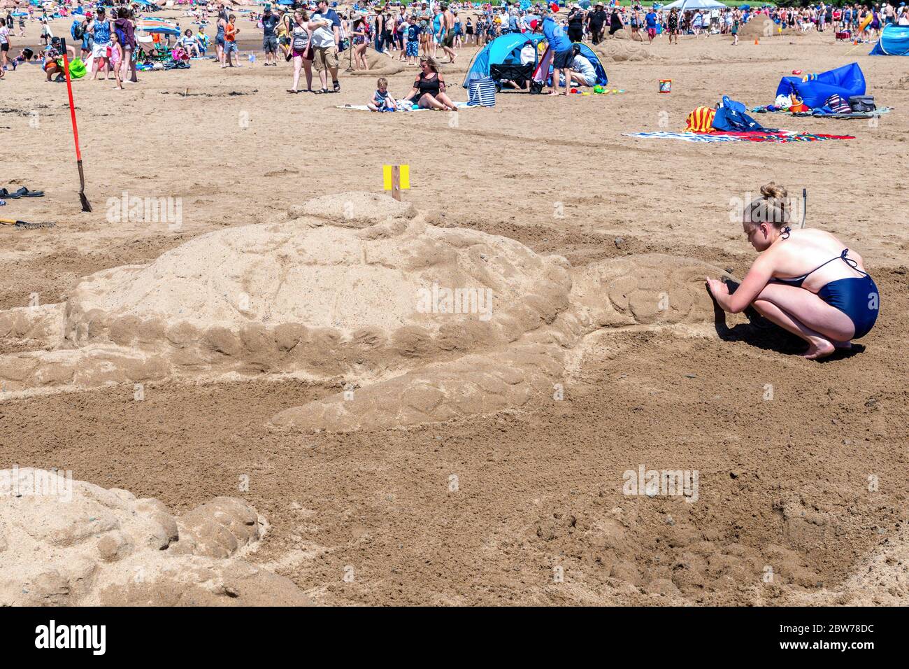 New River Beach, New Brunswick, Kanada - 7. Juli 2018: Der jährliche Wettbewerb für Sandskulpturen. Eine Frau formt eine Schildkröte. Stockfoto