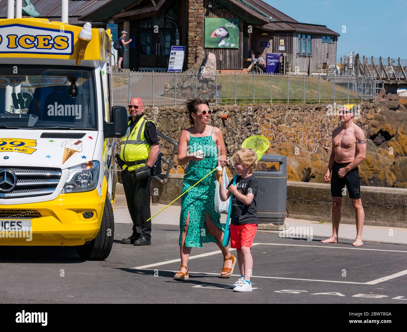 North Berwick, East Lothian, Schottland, Großbritannien, 30. Mai 2020. UK Wetter: Sonnenhungrige im beliebten Badeort an einem luftigen, aber sehr warmen sonnigen Tag fühlen sich an, als ob die Stadt nach Lockdown wieder normal wird. Der Eiswagen ist wieder am Meer. Eine Frau und ein Junge kaufen Eis bei heißem Wetter Stockfoto