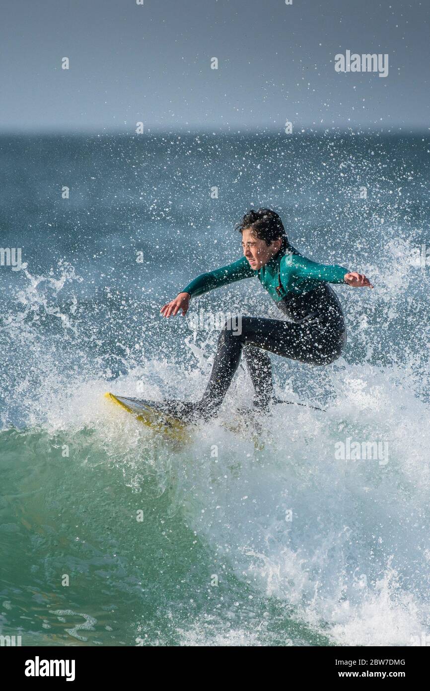 Ein junger Teenager surft bei wilden Surfbedingungen auf dem Kamm einer Welle im Fistral in Newquay in Cornwall. Stockfoto