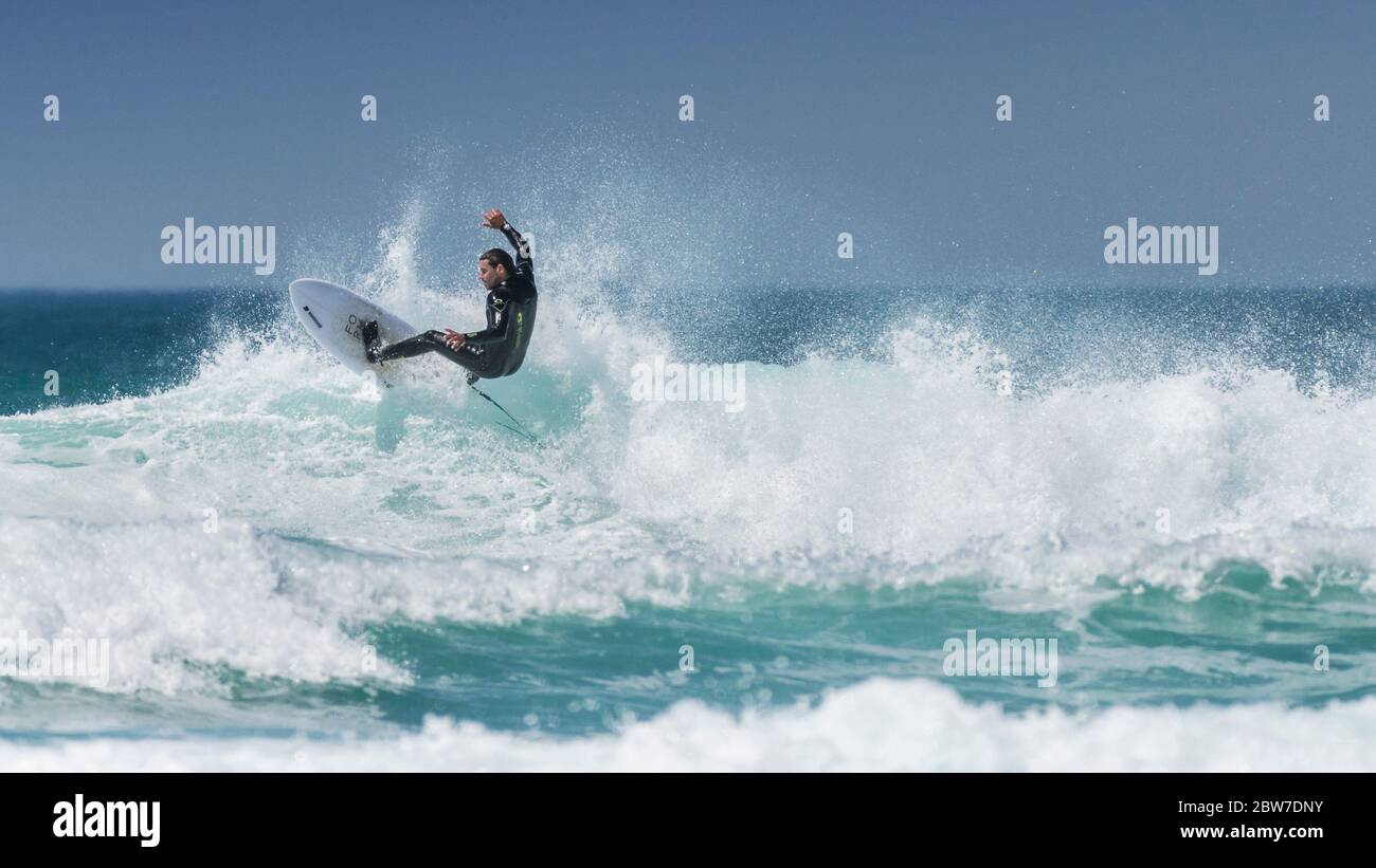 Ein Panoramabild von spektakulärer Action, während ein Surfer eine Welle bei Fistral in Newquay in Cornwall reitet. Stockfoto