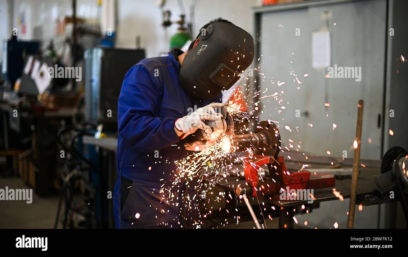 Arbeiter, der einen Winkelschleifer betreibt und viele Funken erzeugt Stockfoto