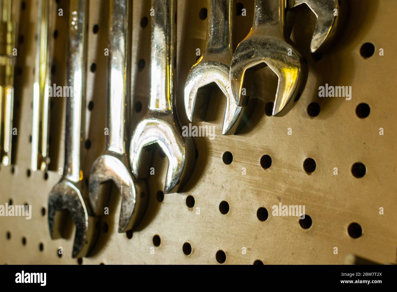 Verschiedene Halbmondschlüssel hängen an einer Lochplatte in einer Werkstatt Stockfoto