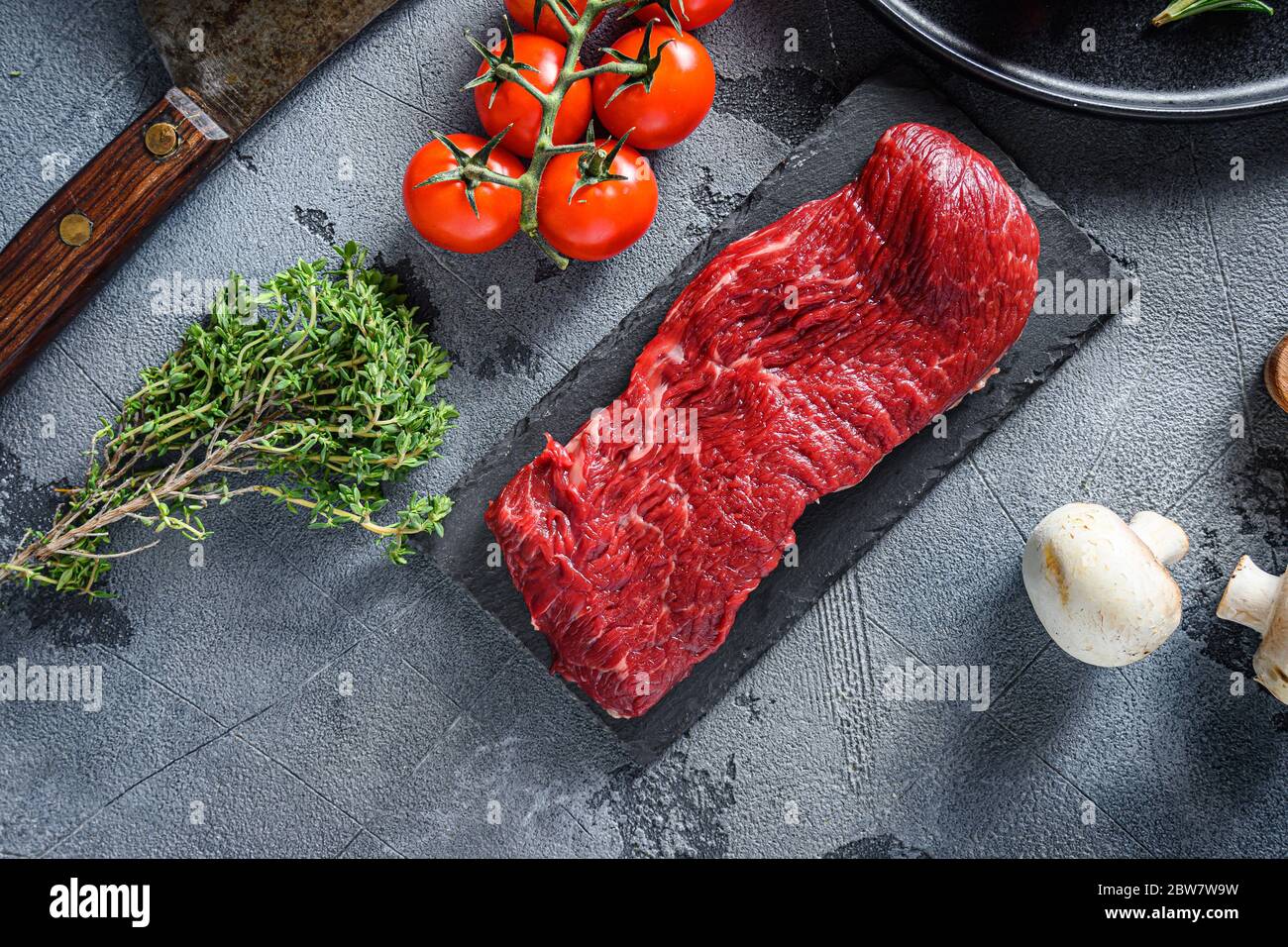 Rohe Tri-Spitze, Boden Sirloin geschnitten Steak auf schwarzem Schiefer roh Bio-Lebensmittel, marmoriertes Rindfleisch über andere alternative Schnitte mit Kräutern Tomaten Pfefferkörner über Stockfoto