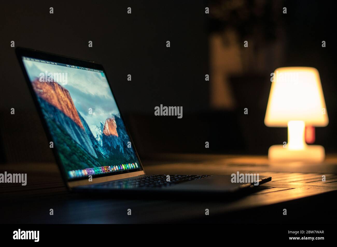 Aufklapptes MacBook Pro in der Dämmerung mit Lampe im Hintergrund Stockfoto