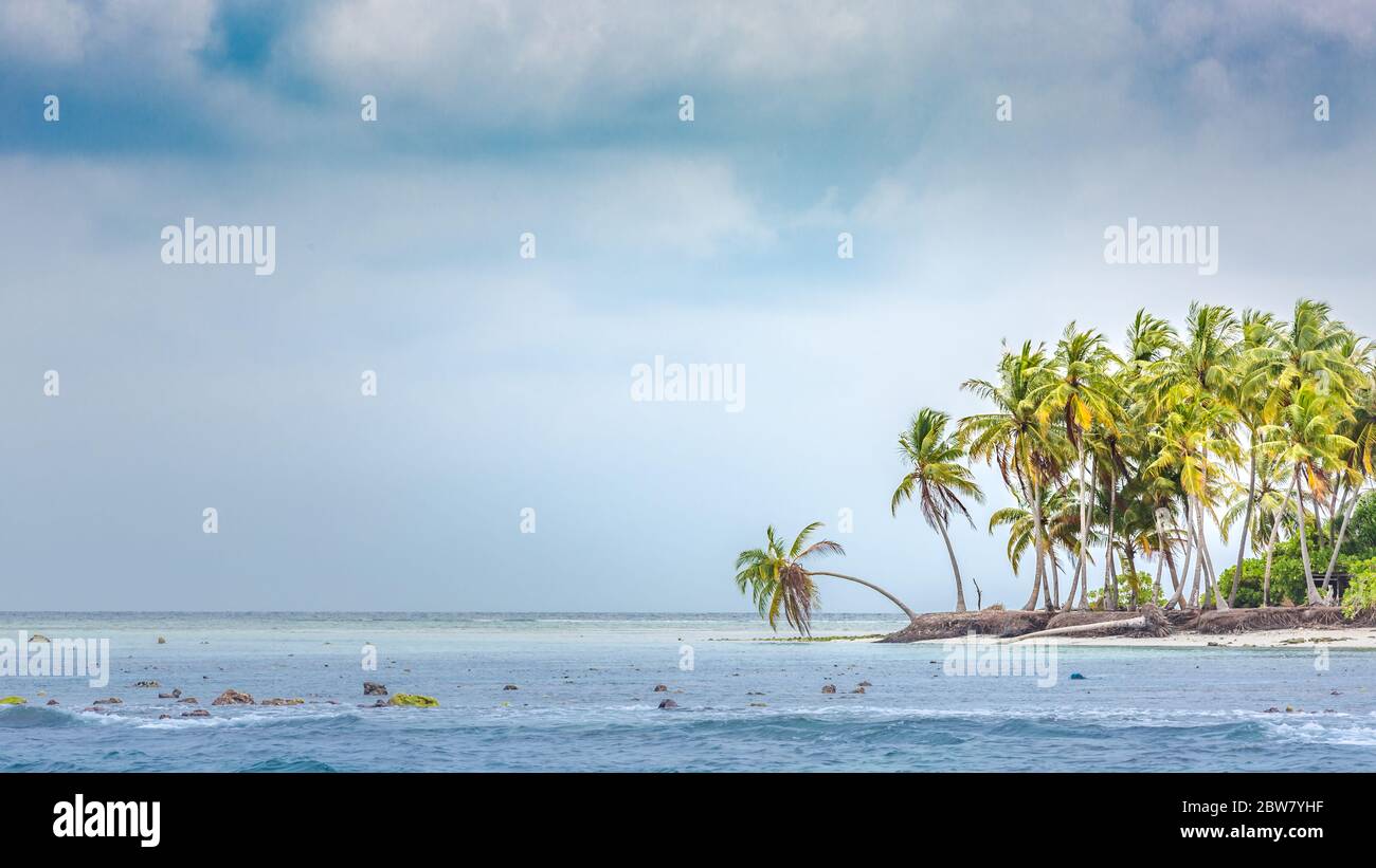 Wolkige tropische Inselküste oder -Küste, Palmen und Sturmwolken mit welligen Meer- oder Meerwasser. Exotische Destination Insel Küste Stockfoto