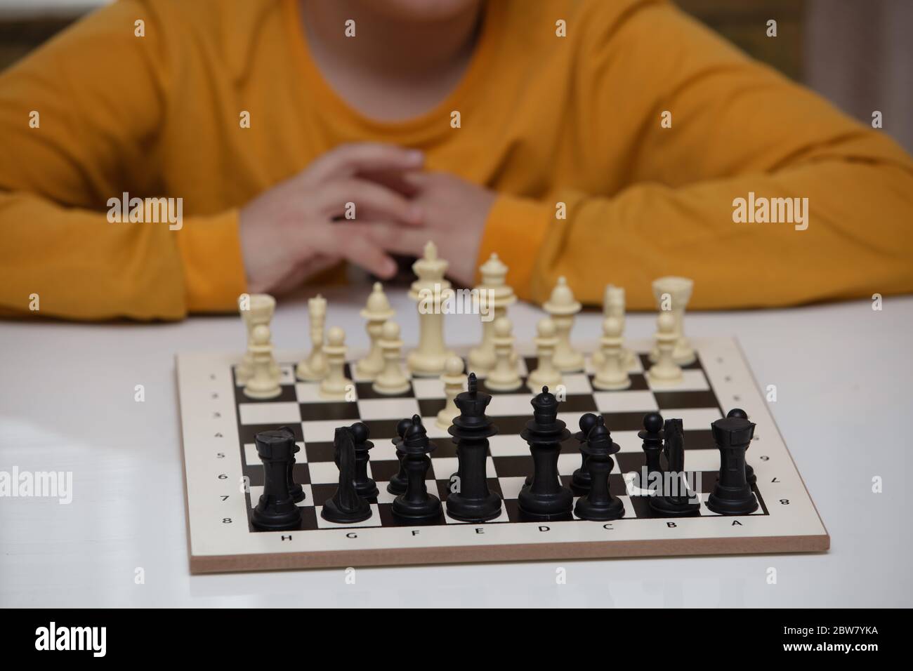 Sitzt an einem Tisch und spielt Schach. Das Kind konzentrierte sich auf das Spiel Stockfoto