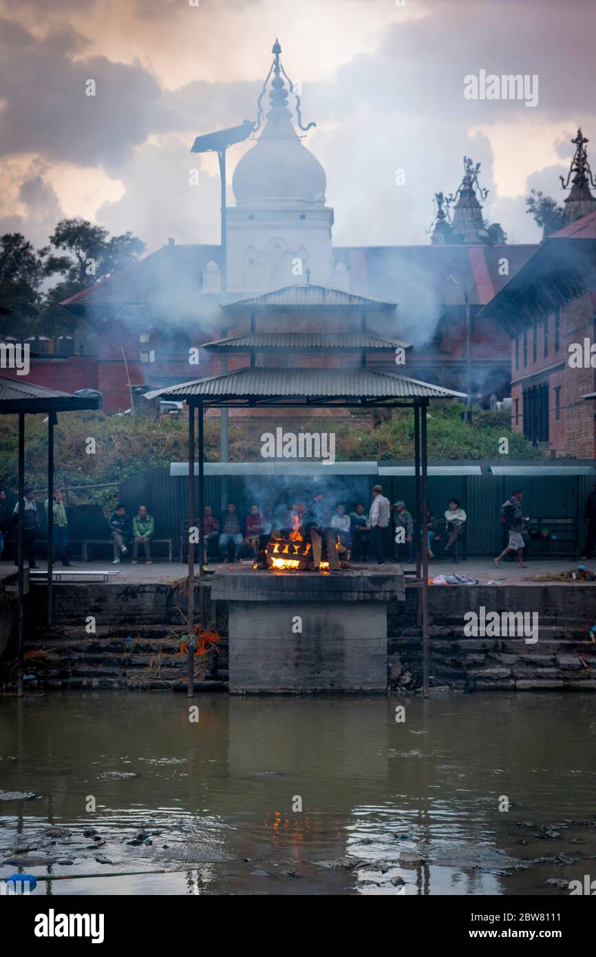 Die Verwandten warten auf einen Scheiterhaufen. Bagmati Fluss, Arya Ghat, Pashupatinath Tempel. Kathmandu, Nepal, Nepalesisch, Asien, Asien, Himalaya. Stockfoto