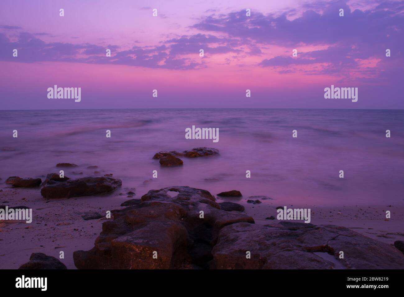 Friedliche Aussicht auf die Steine am Meer am frühen Morgen violetter Sonnenaufgang in Kuwait Beach. Stockfoto