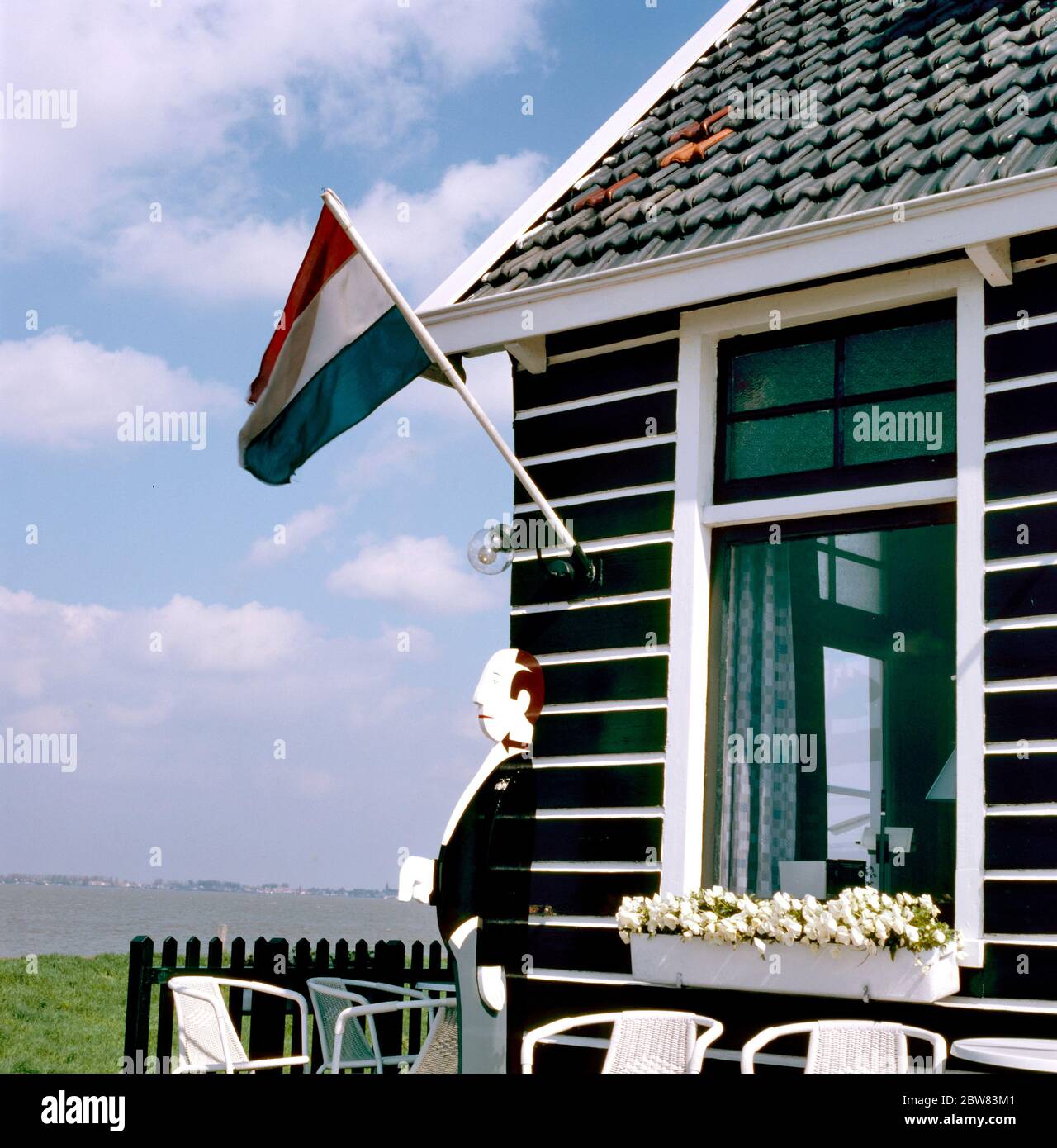 Café im Freien mit leeren Stühlen, Holzbutler und holländischer Nationalflagge am IJselmeer in Marken, Holland Stockfoto