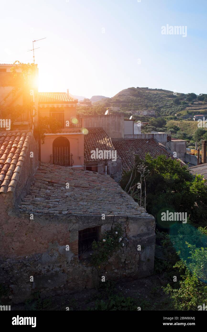 Am Rande auf einem alten Hügel Stadt in Sizilien, mit einem Flare von der hellen untergehenden Sonne. In der Ferne befinden sich alte Gebäude und Hügel. Stockfoto
