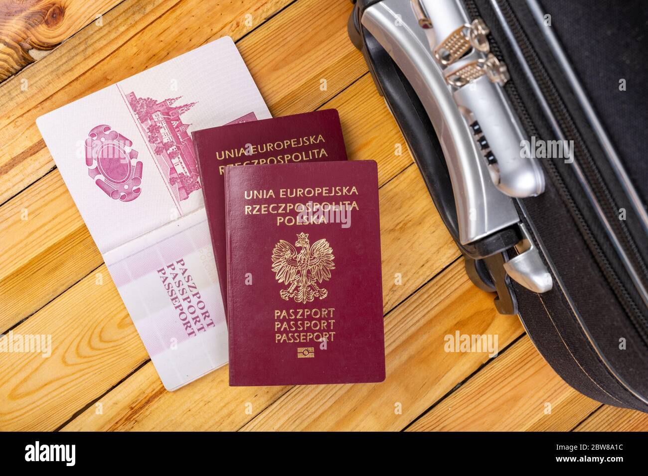 Großer Reisekoffer und polnischer Reisepass. Gepäck für Reisen ins Ausland vorbereitet. Dunkler Hintergrund. Stockfoto
