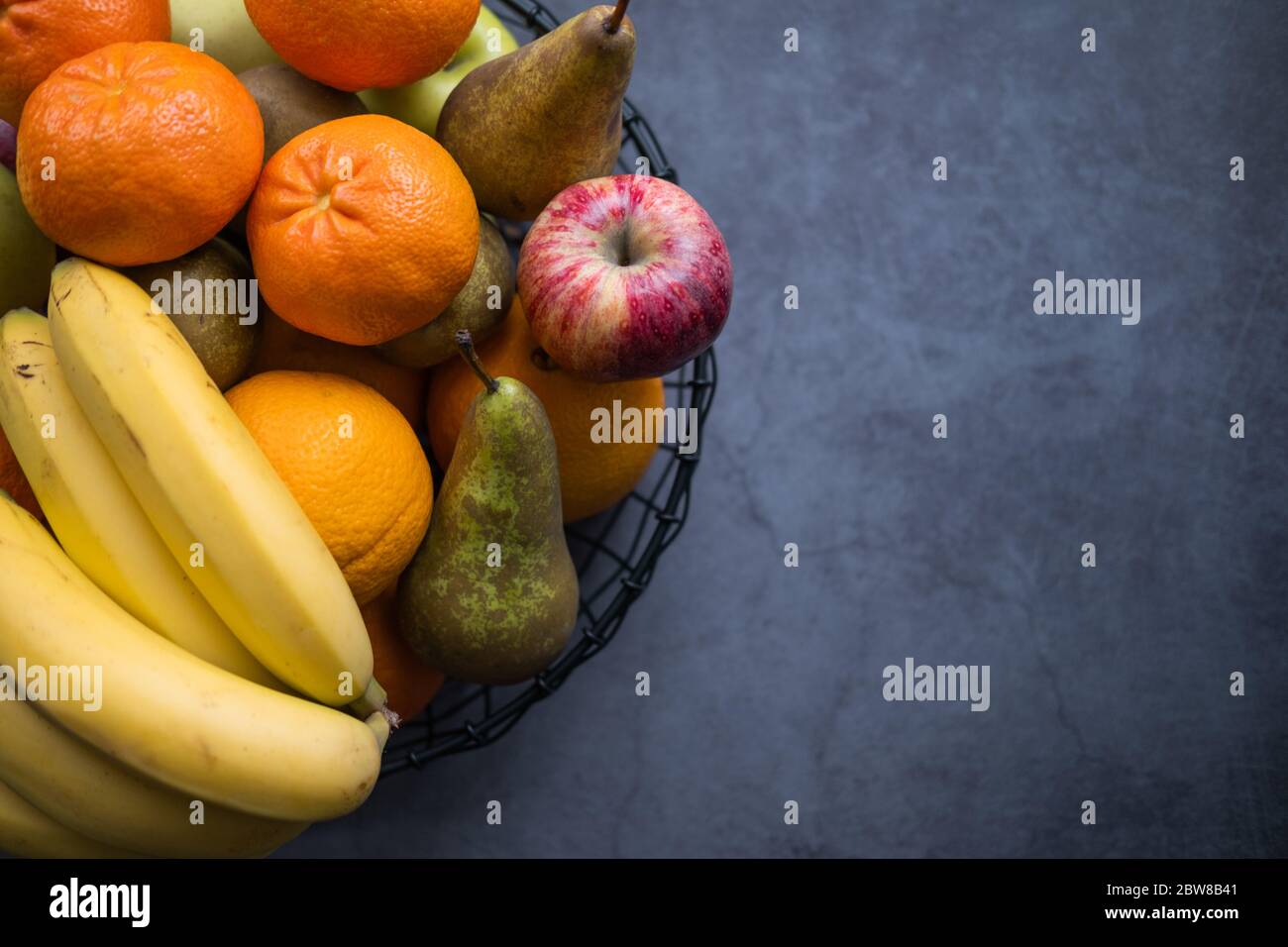 Vielfalt an Früchten wie Äpfel, Bananen, Birnen und Orangen auf einem Fruchtaufstrich auf betonierten Hintergrund. Gesunde Ernährung. Draufsicht. Kopierbereich rechts. Stockfoto