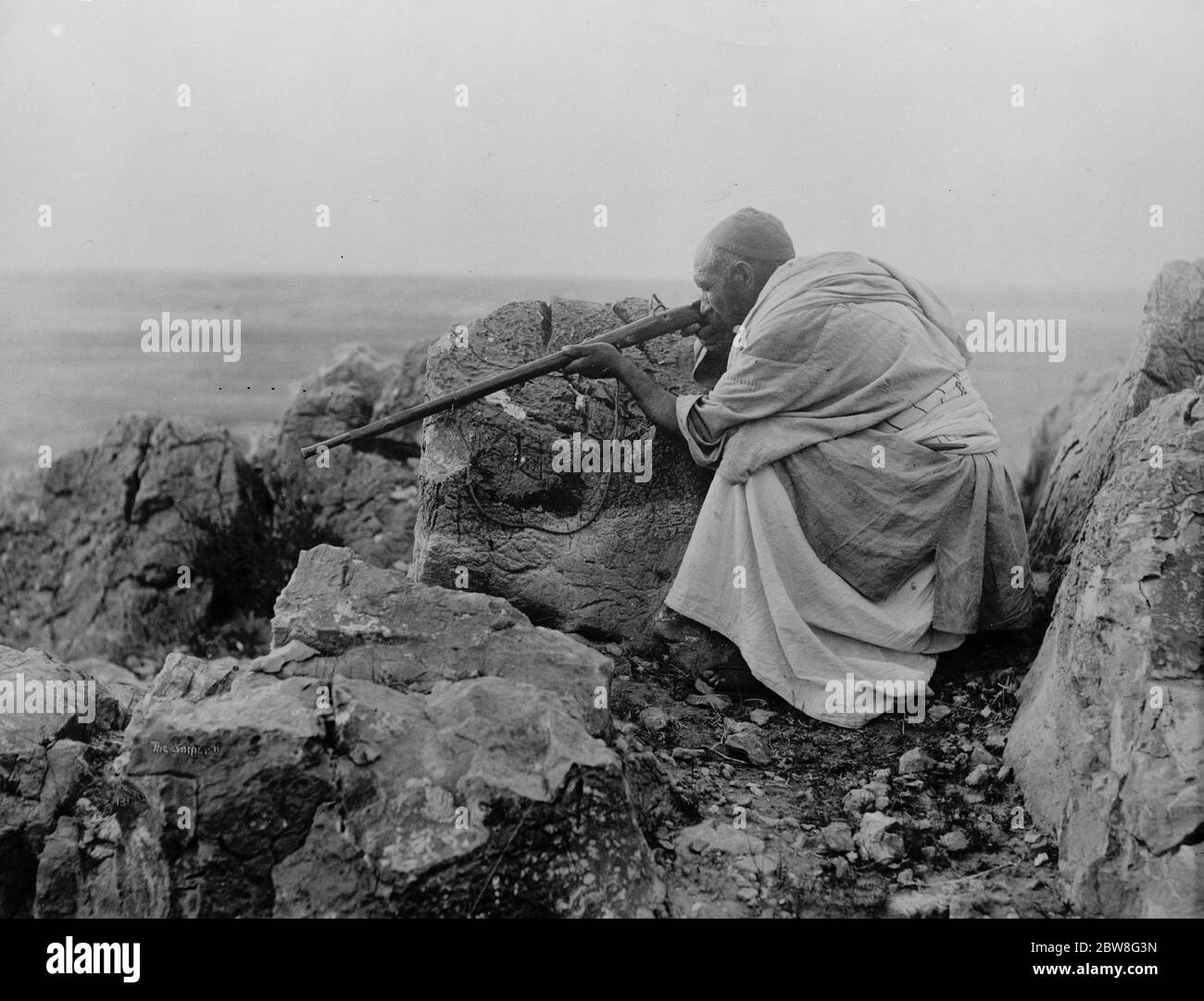 Besorgt in der Peschawar Ärger . Ein typischer Afridi Scharfschütze hinter den Felsen. August 1930 Stockfoto