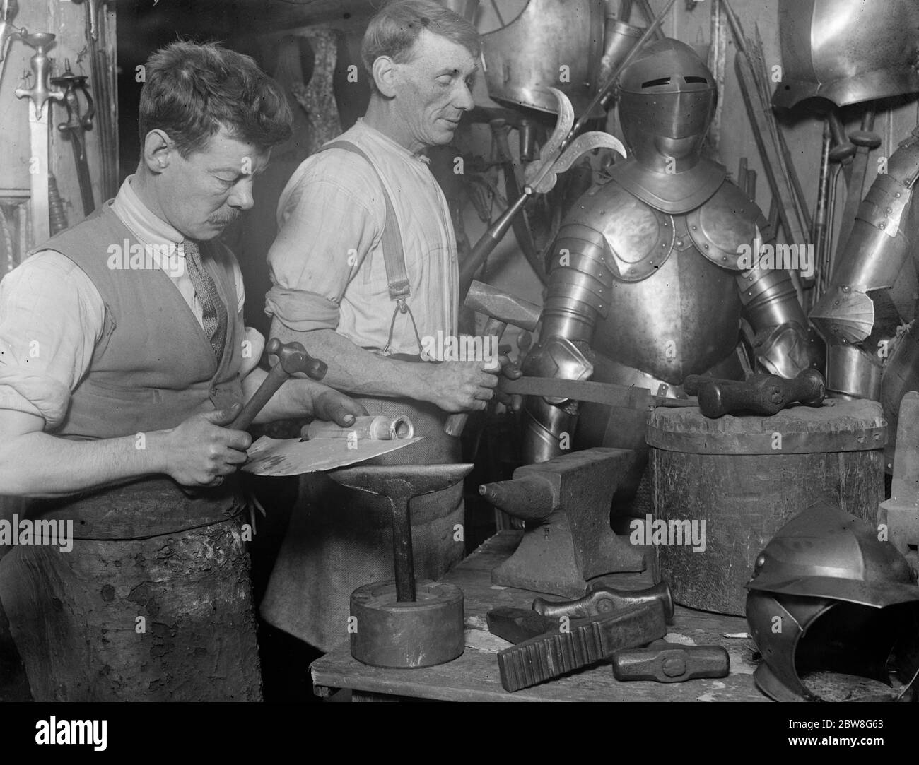 Die letzte einer langen Reihe von Rüstern . Herr Sam Rex bei der Arbeit an einer Schlachtaxt, während sein Assistent ein Schwert macht. 26. September 1930 Stockfoto