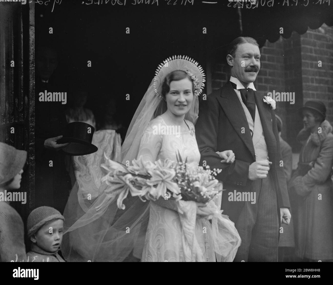 Schöne Braut 's markante Kopfkleid. Die Ehe von Miss Ann Bovill und Herr C P A Burgess, bei Holy Trinity, Brompton. Die Braut und der Bräutigam verlassen die Kirche . Dezember 1932 Stockfoto