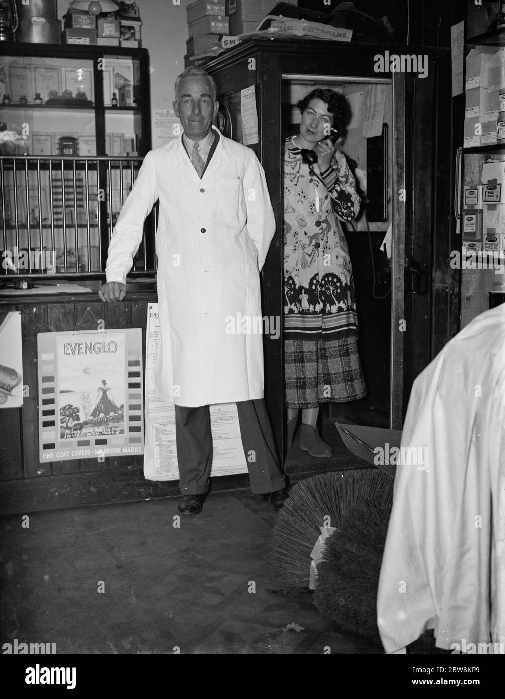 Herr George May, Postmaster von Downe, Kent durch seine Post-Office-Schalter mit seiner Frau, Mai, in der Telefonbox. Oktober 1937. Stockfoto
