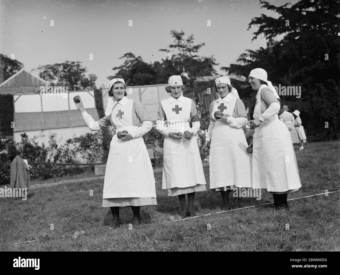 Red Cross Krankenschwestern immer bereit, ihre Hände an der Kokosnuss schüchtern versuchen. 1935 Stockfoto