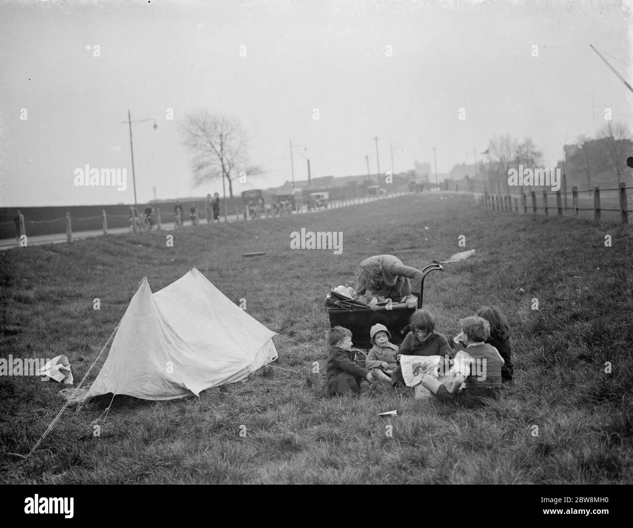 Kinder haben ein Picknick auf einem Stück Gras neben der Straße. 1938 Stockfoto