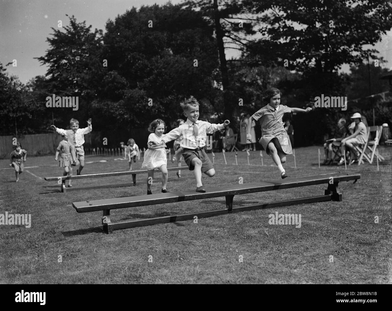 Kleine Kinder springen über Bänke während eines Rennens an ihrem Schulsporttag. 1935 Stockfoto