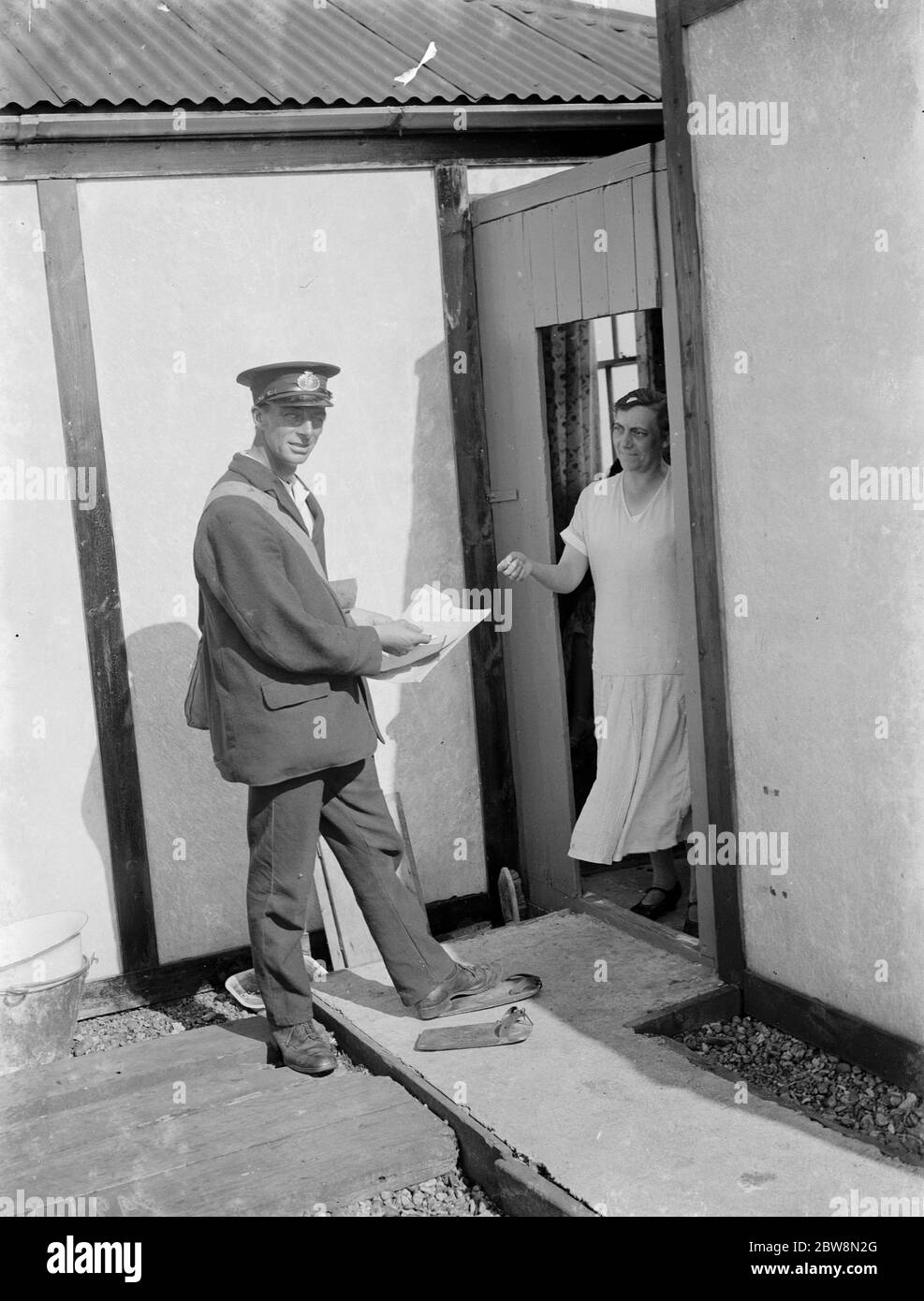 Herr Freathy liefert Post an Menschen, die in der Nähe des Kiesstrandes bei Dungeness leben, mit seinen speziellen Holzschuhen, die ihm helfen, über die Kieselsteine zu gehen. 1935 Stockfoto