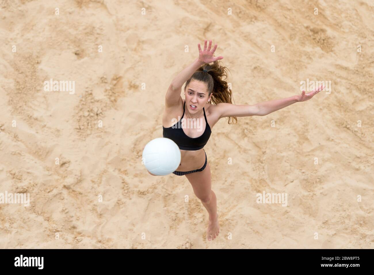 Junge Frau mit weißem Ball spielen Volleyball am Strand. Sommerurlaub und Sportkonzept Stockfoto