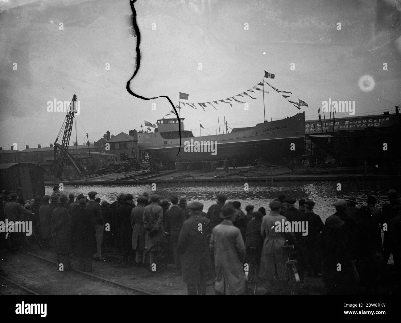 Zuschauer warten darauf, das neue Schiff zu starten, während das Schiff breitseitig auf der Slipanlage der Werft von James Pollock and Sons in Faversham, Kent, sitzt. 1935 Stockfoto