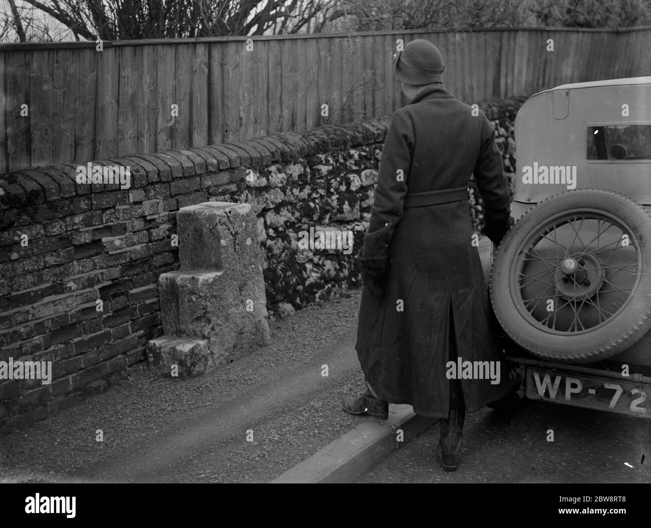 Alt und neu. Eine Frau Autofahrer sieht sich Befestigungsblöcke für Reiter am Straßenrand. 1935 Stockfoto