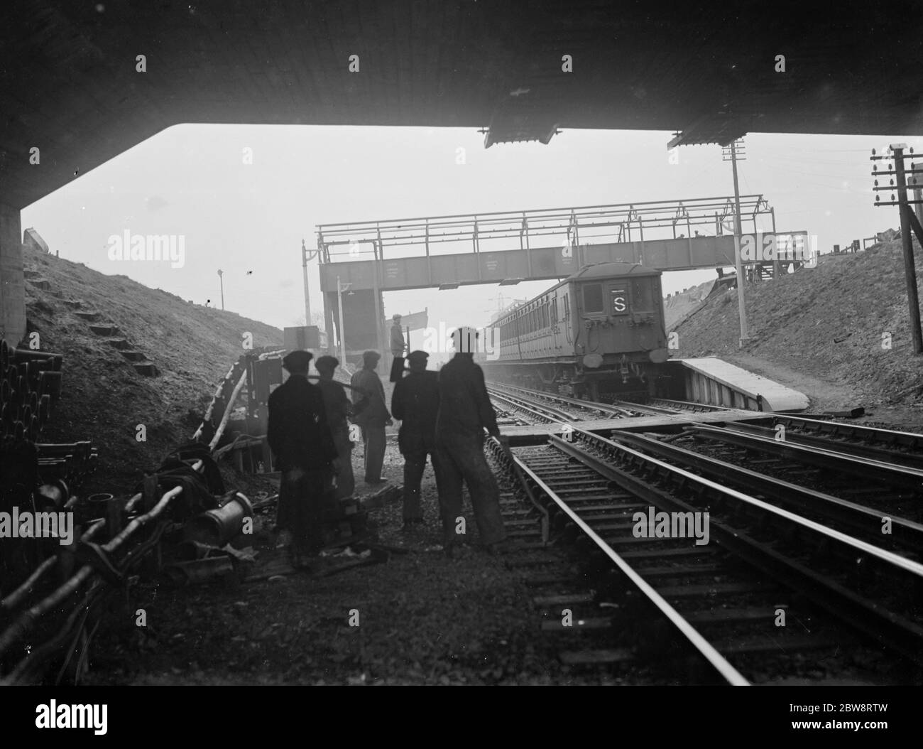 Bahnarbeiter auf den Gleisen am Bahnhof Falconwood, wenn ein Zug vorbeifährt. 1935 Stockfoto