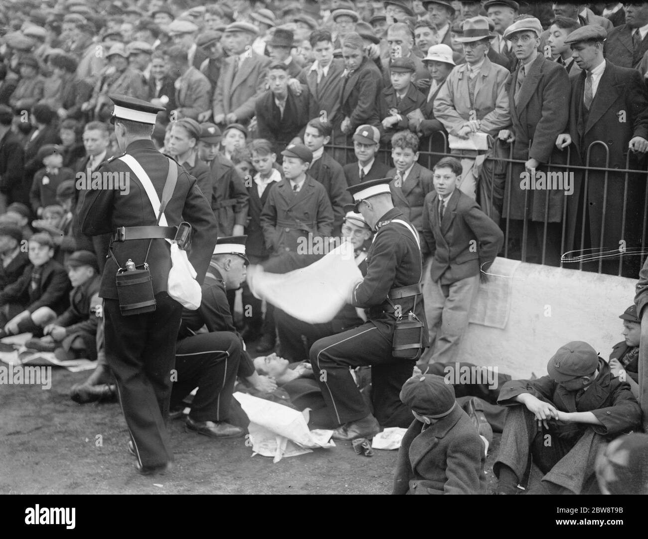 Fußballspiel: Arsenal Football Club gegen Charlton Athletic Football Club im Highbury Stadium, London. Erste Helfer sehen einen Verletzten. 1936 Stockfoto