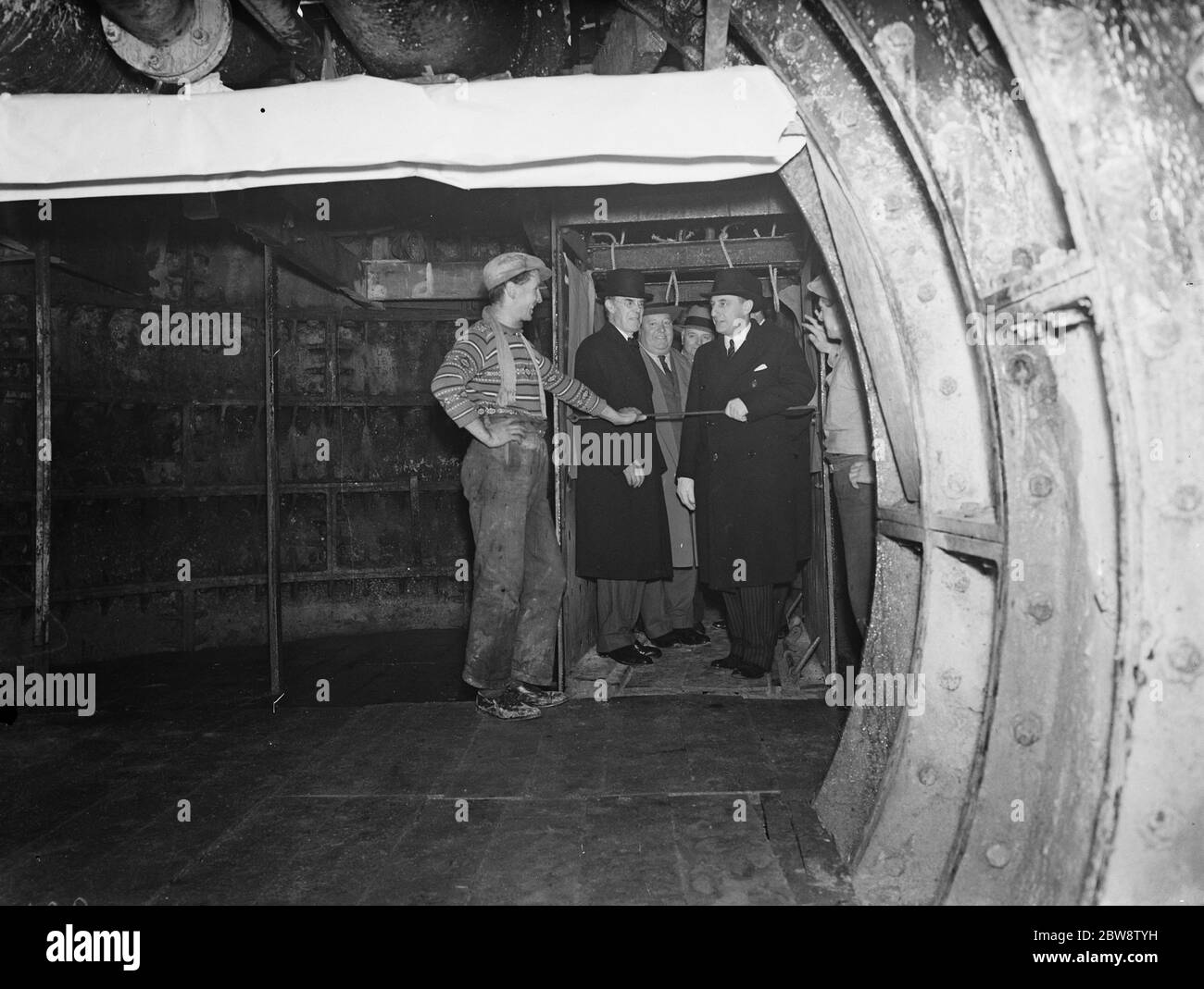 Der Bau des Dartford Tunnels, wo vor kurzem ein Pilottunnel fertiggestellt wurde. Der Verkehrsminister Leslie Burgin sprach mit einem Arbeiter am Boden des Schachts über seinen Besuch im Dartford-Tunnel. 1938 1938 Stockfoto