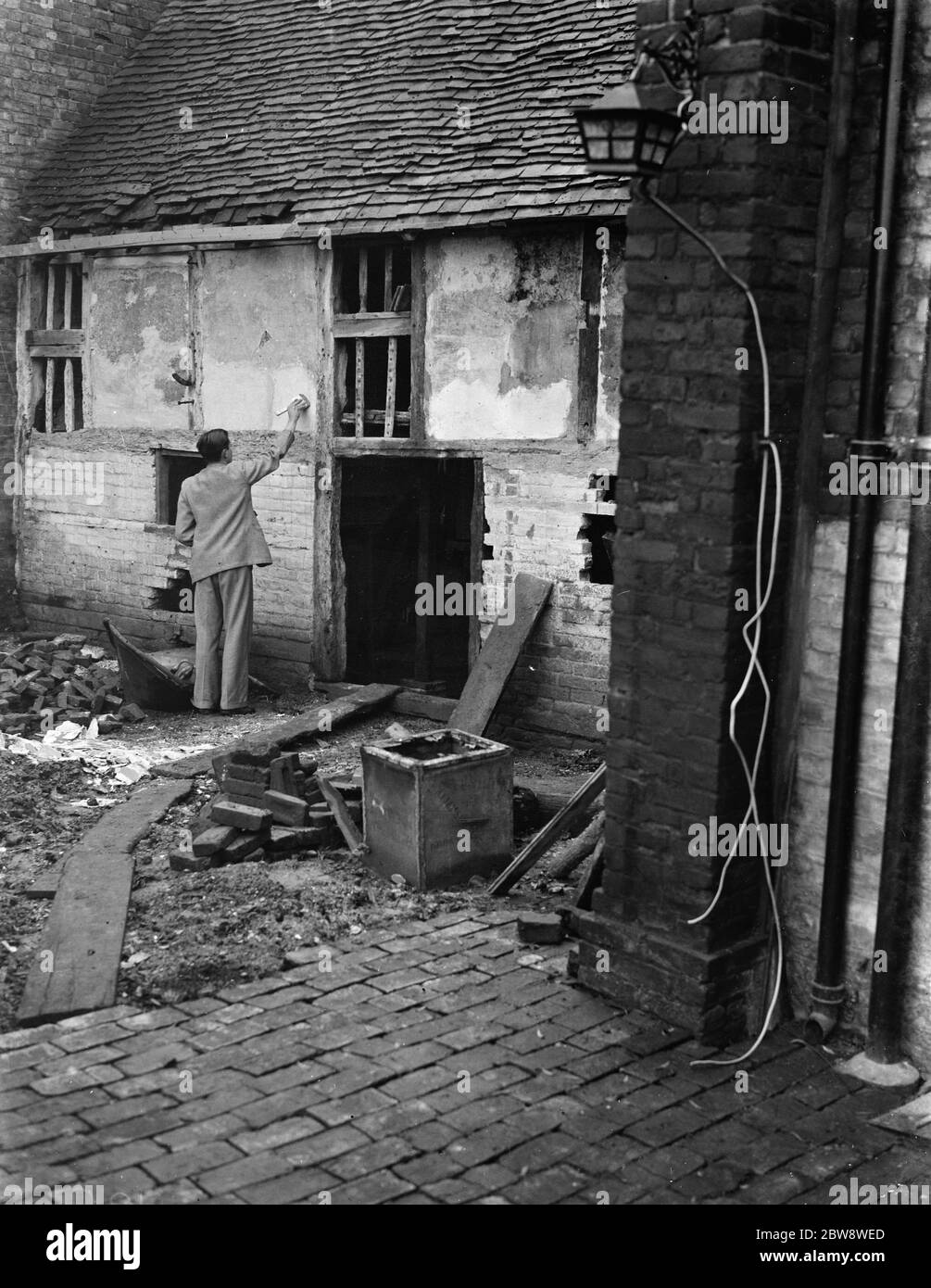Herr Greenfield putzt die Wand eines alten verfallenen Häuschens, das als Museum in Eynsford, Kent, genutzt werden soll. 12 Dezember 1938 Stockfoto