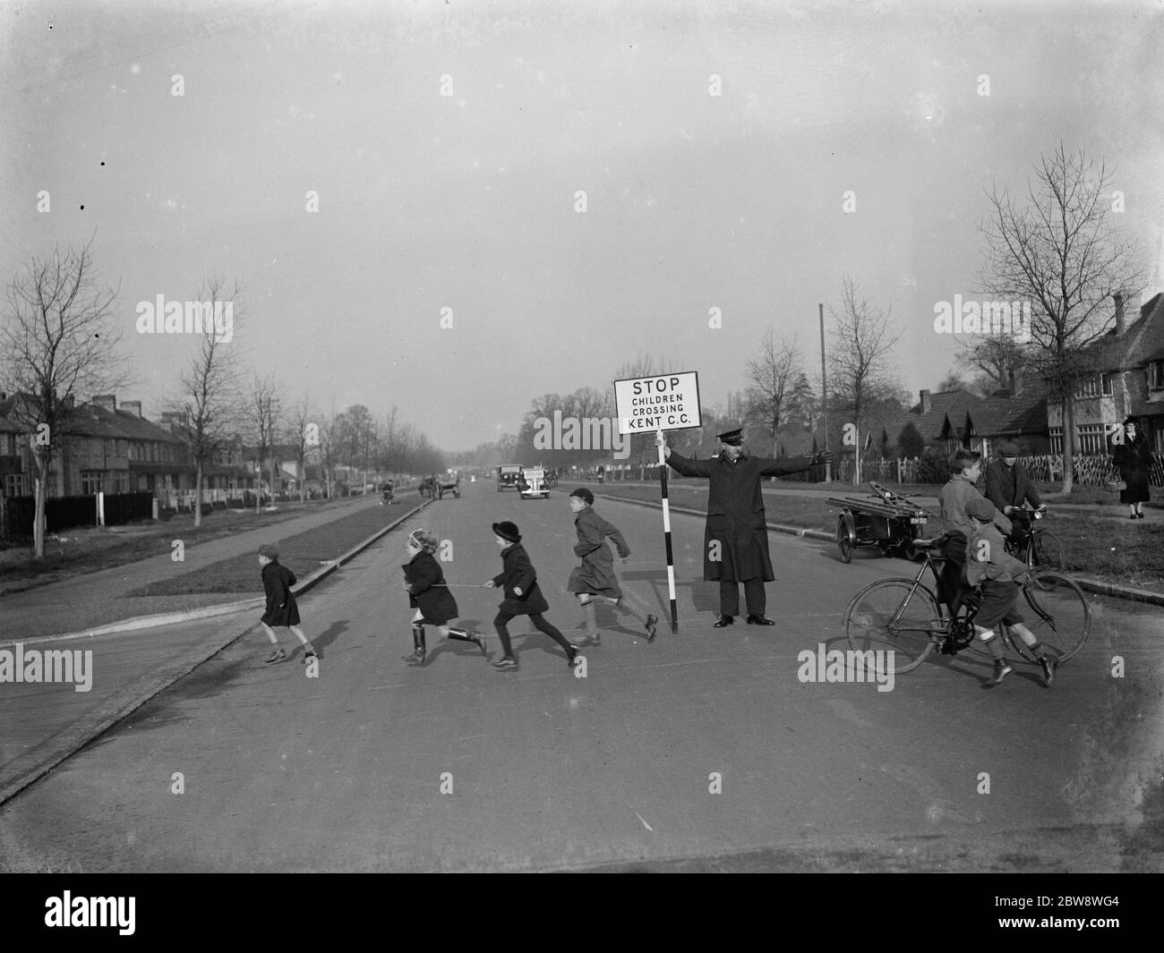 Straßenwärter von Kent County Council, mit einem Schild, hilft Kindern in St. Mary Cray über die Straße. 1938 Stockfoto