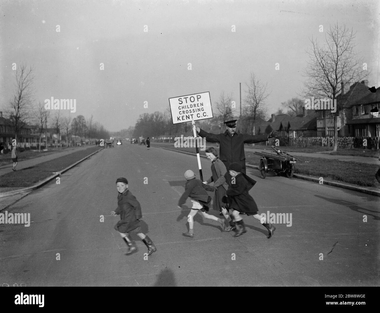 Straßenwärter von Kent County Council, mit einem Schild, hilft Kindern in St. Mary Cray über die Straße. 1938 Stockfoto