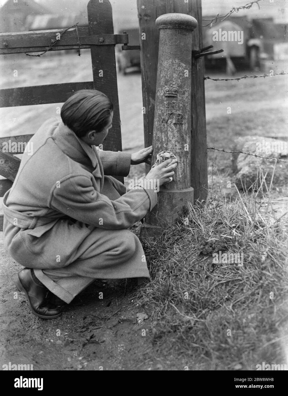 Ein Mann benutzt ein Tuch, um zu versuchen und reinigen Sie einen Grenzposten. 1937 Stockfoto