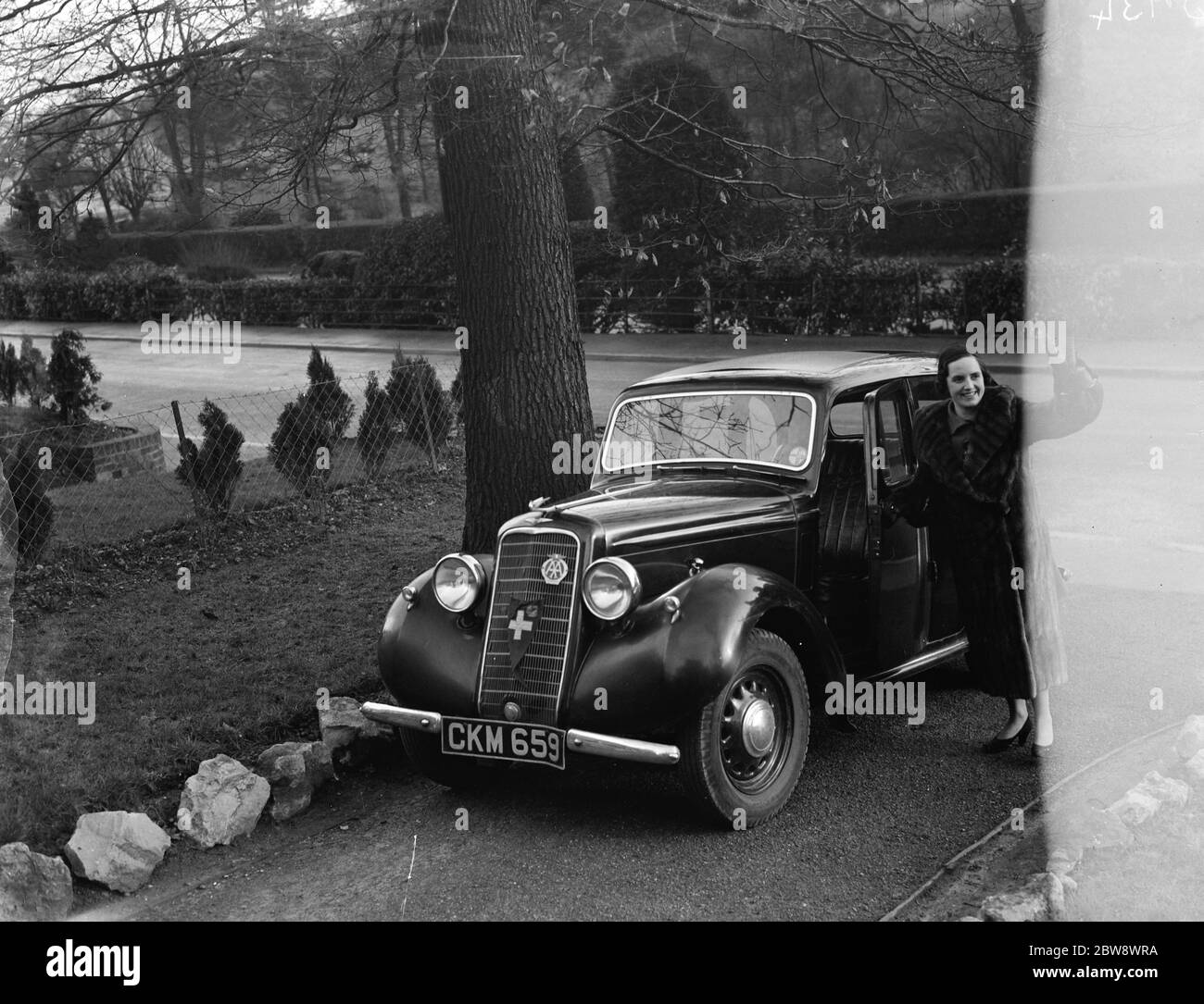 Frau Zehnder winkt neben ihrem Auto, vor ihrem Haus. Werbeaufnahmen für den Daily Mirror gemacht. 1937 Stockfoto