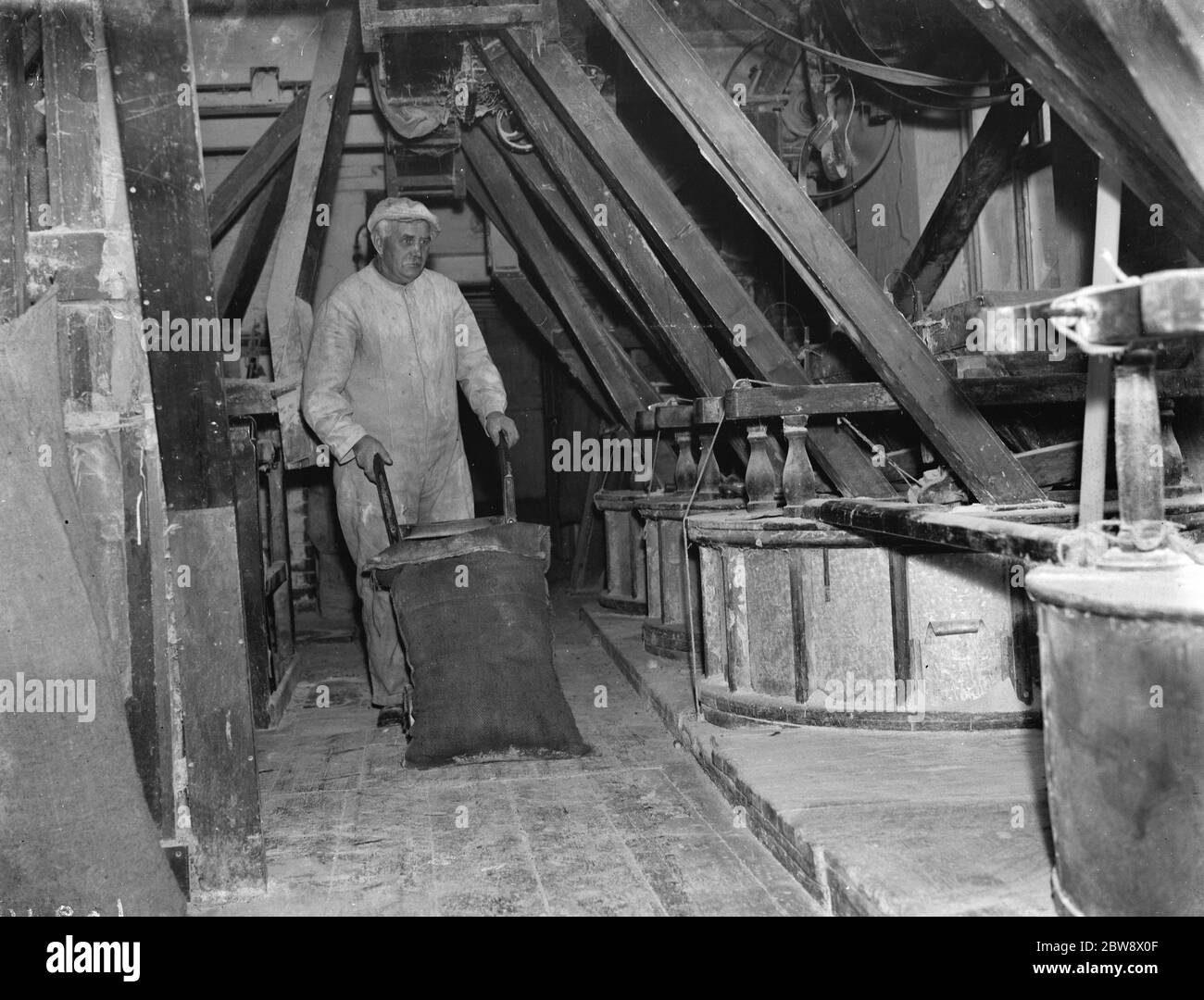Ein Arbeiter, der einen Sack mit einem Wagen in der altmodischen Mühle in Erith, London, verlagern. 14. Januar 1939 Stockfoto